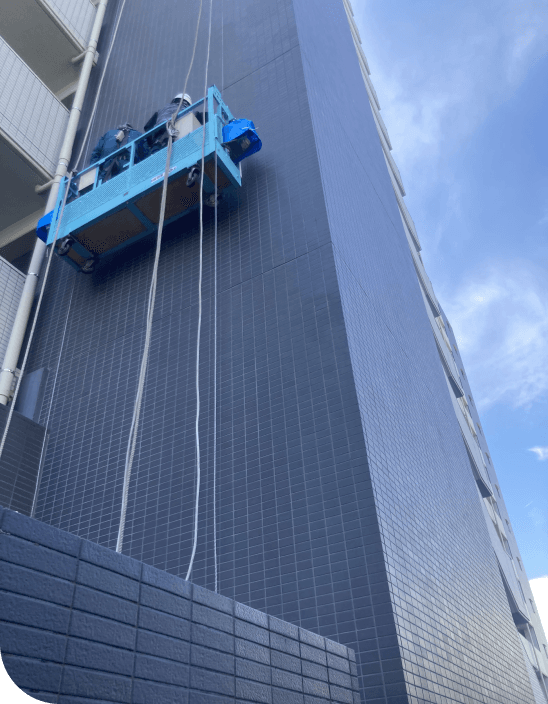 ゴンドラに乗って高層マンションの外壁を施工する作業員