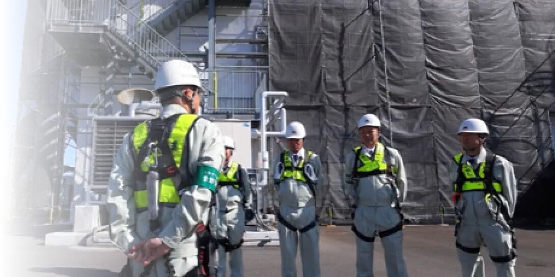 足場の前に集まり作業前朝礼を行うヘルメット姿の作業員