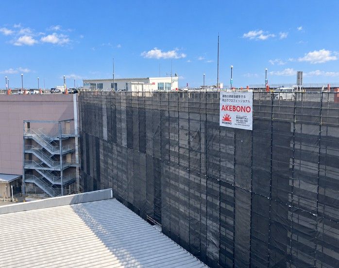 防音シートで覆われた改修工事中の建物とアケボノの工事看板