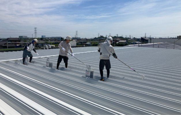 工場の屋根で塗装作業をする職人